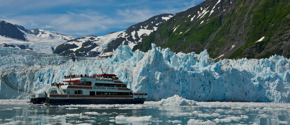 A massive, blue Alaskan glacier calving into the sea